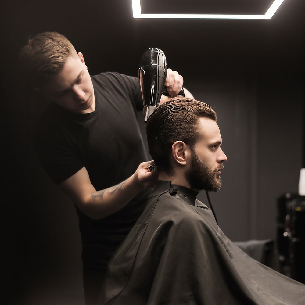 Friseur föhnt die Haare eines männlichen Kunden